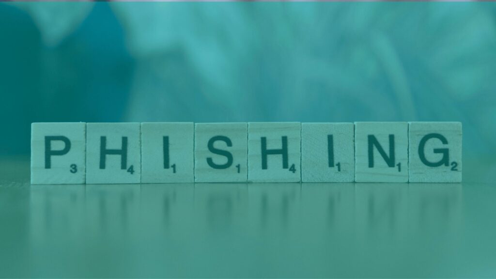 Wooden Scrabble tiles spelling out the word phishing on a blurred background.
